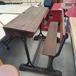 Tweedehands schoolbanken en stoelen met houten zittingen en zwarte metalen onderstellen in de winkel