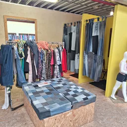Winkelvloer met kledingrekken, etalagepoppen en uitgestalde tweedehands kleding in verschillende kleuren