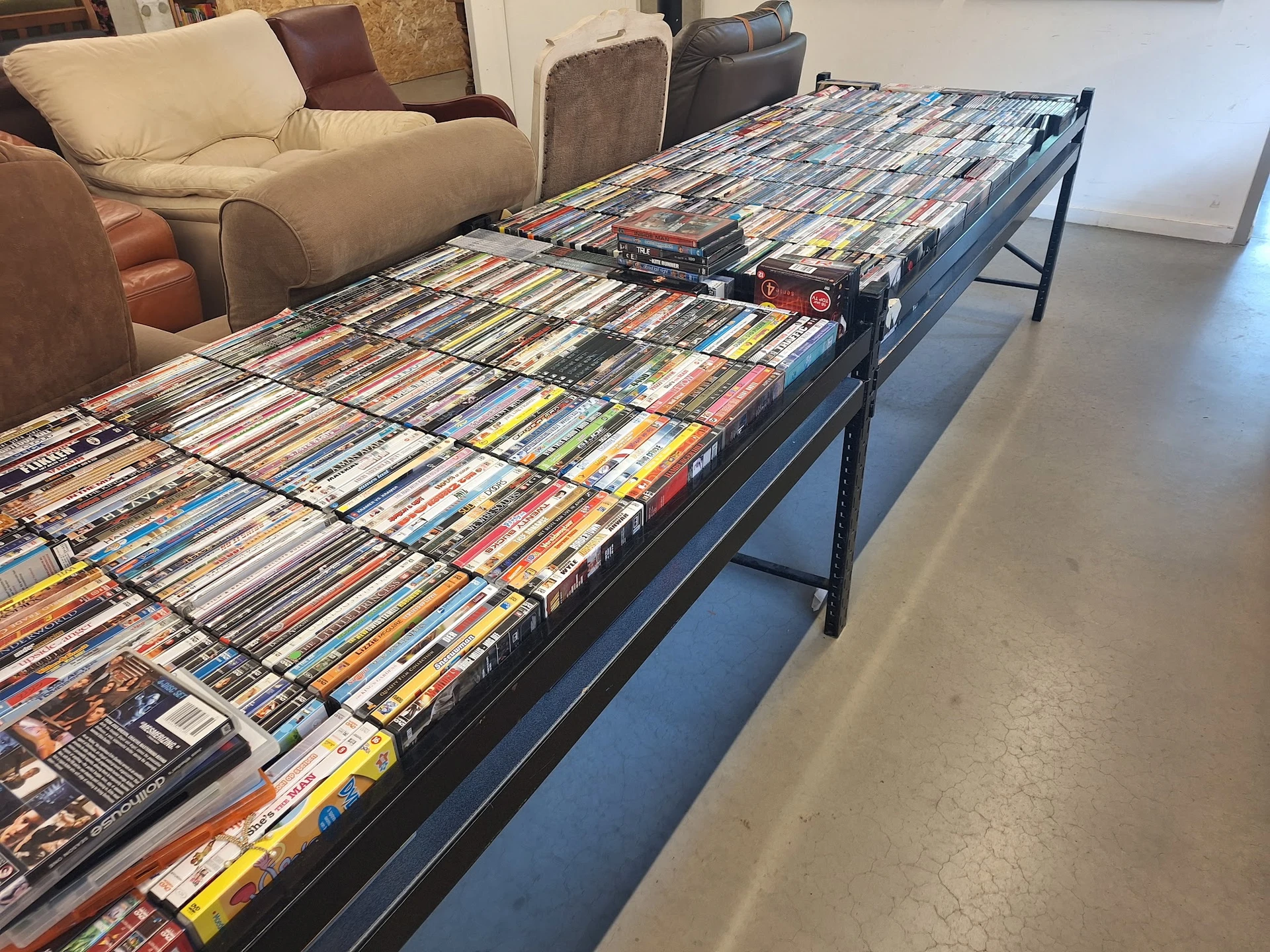 Lange tafel vol met tweedehands dvd's en blu-rays uitgestald op een winkelvloer