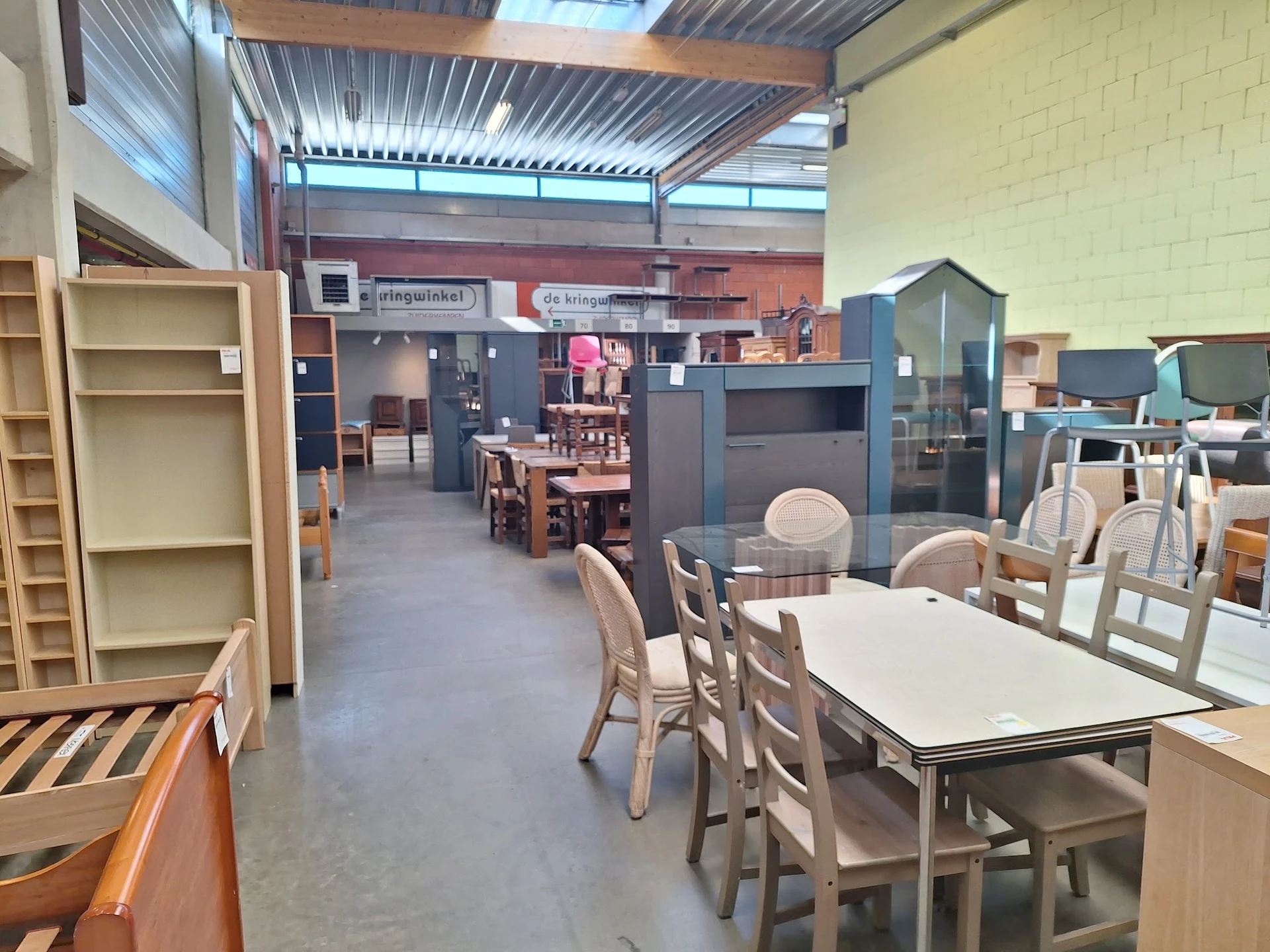 Winkelinterieur met tafels, stoelen, stellingen en diverse meubelstukken in een groot magazijnruimte
