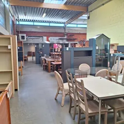 Winkelinterieur met tafels, stoelen, stellingen en diverse meubelstukken in een groot magazijnruimte