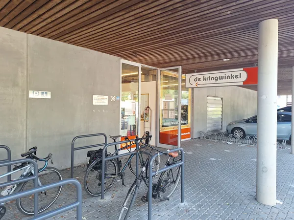 Winkelfront met glazen deuren en 'de kringwinkel' naambordje, fietsenrek daarvoor