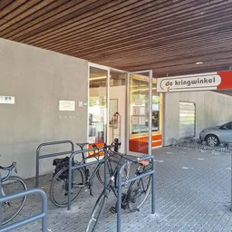 Winkelfront met glazen deuren en 'de kringwinkel' naambordje, fietsenrek daarvoor