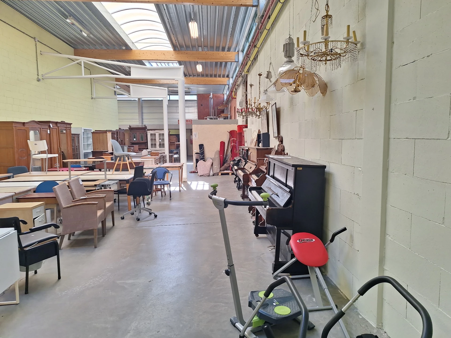 Ruim winkelpand met meubels, lampen en huishoudartikelen uitgestald, skylight in plafond