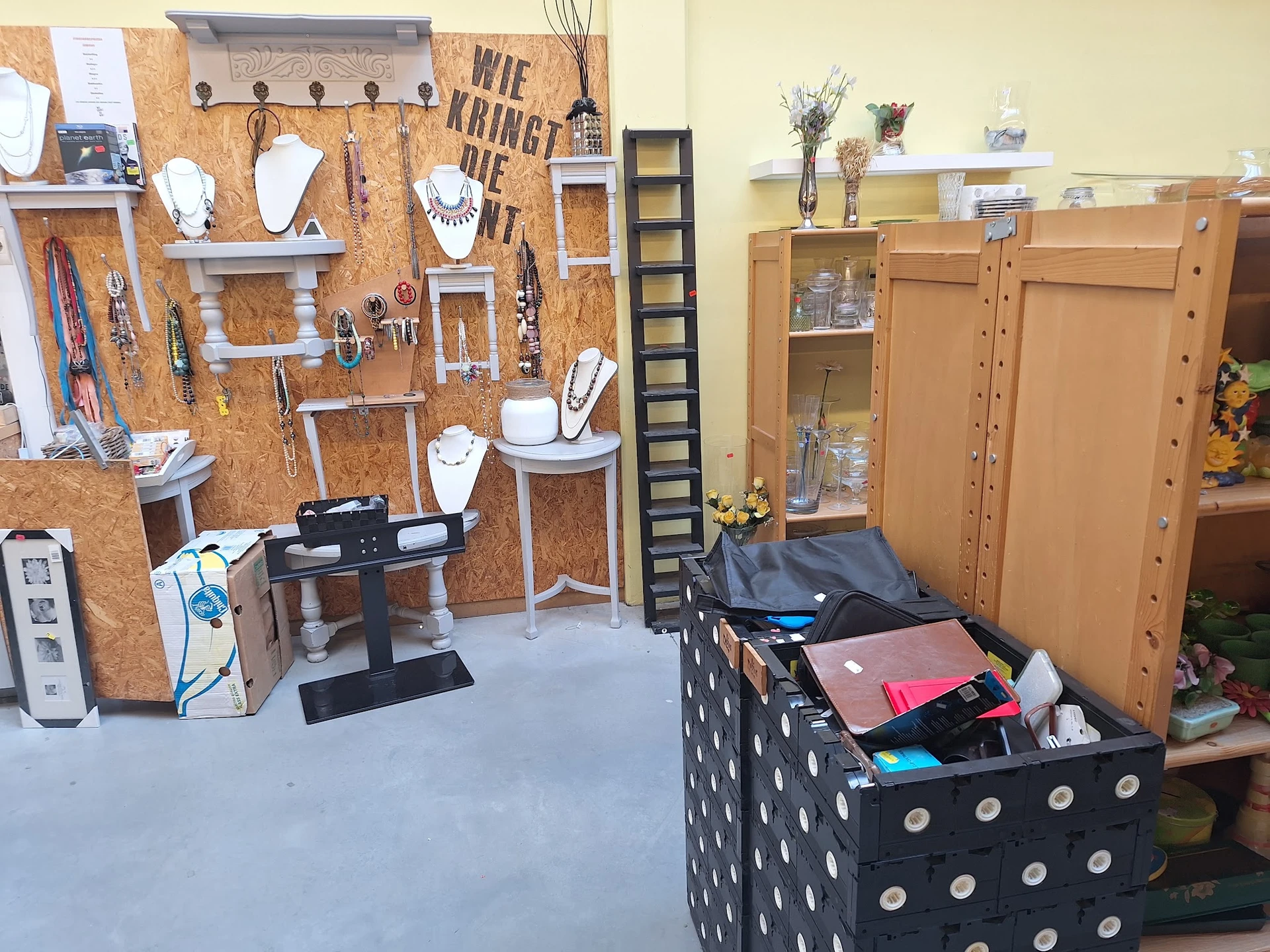 Winkelvloer met uitstalling van sieraden op kurk pegboard, houten kasten en displayboxen met diverse tweedehandsartikelen