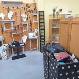Winkelvloer met uitstalling van sieraden op kurk pegboard, houten kasten en displayboxen met diverse tweedehandsartikelen