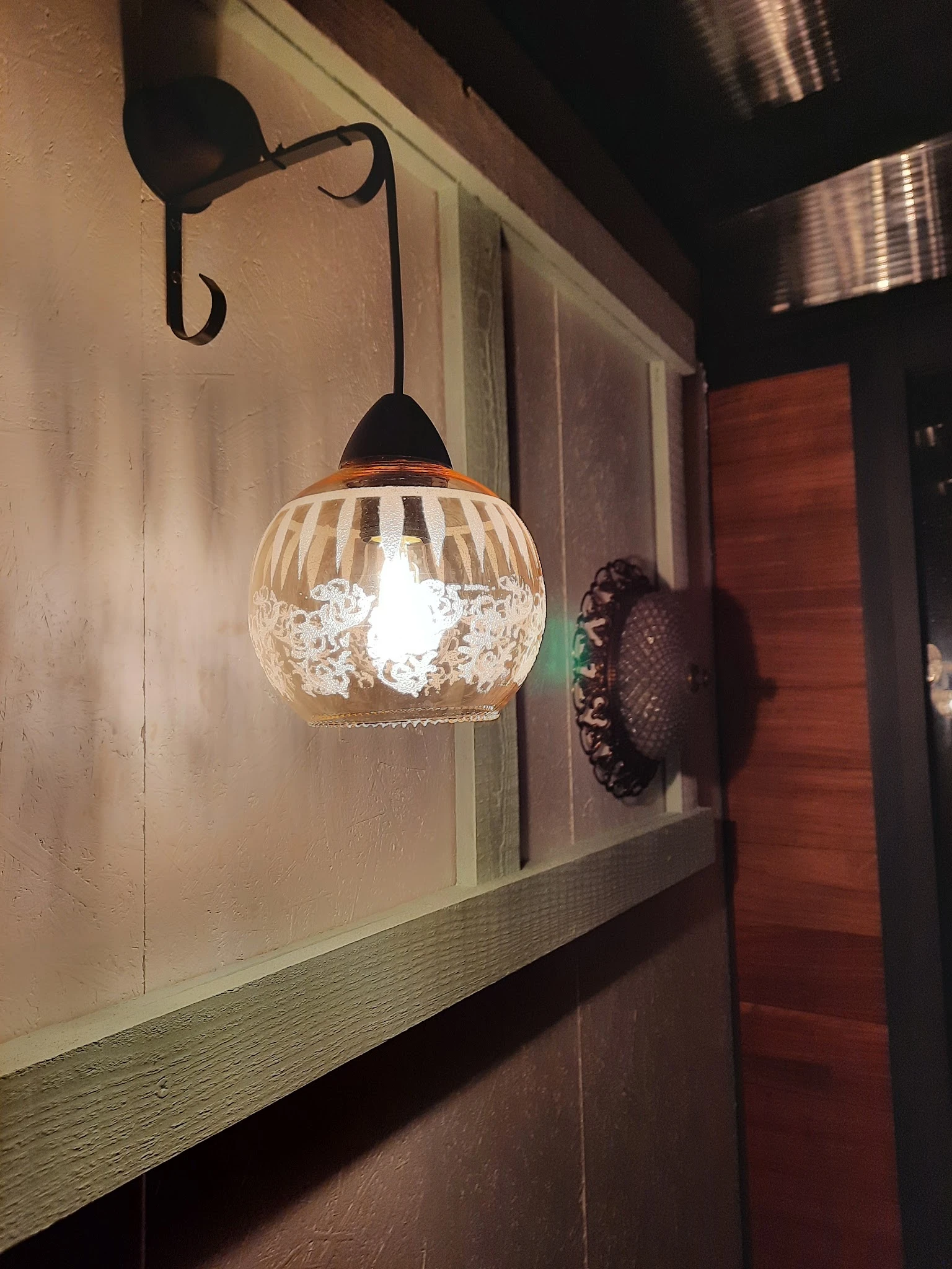Hanglamp met helder geslepen glazen bol en zwarte metalen fitting, verlicht in winkelomgeving