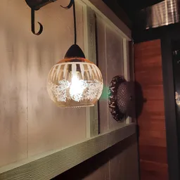 Hanglamp met helder geslepen glazen bol en zwarte metalen fitting, verlicht in winkelomgeving
