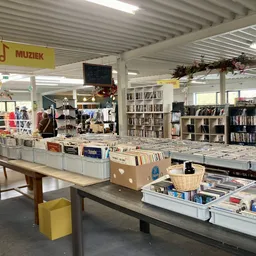 Winkelvloer met tafels vol met cd's, boeken en diverse tweedehands artikelen; boekenkasten op de achtergrond
