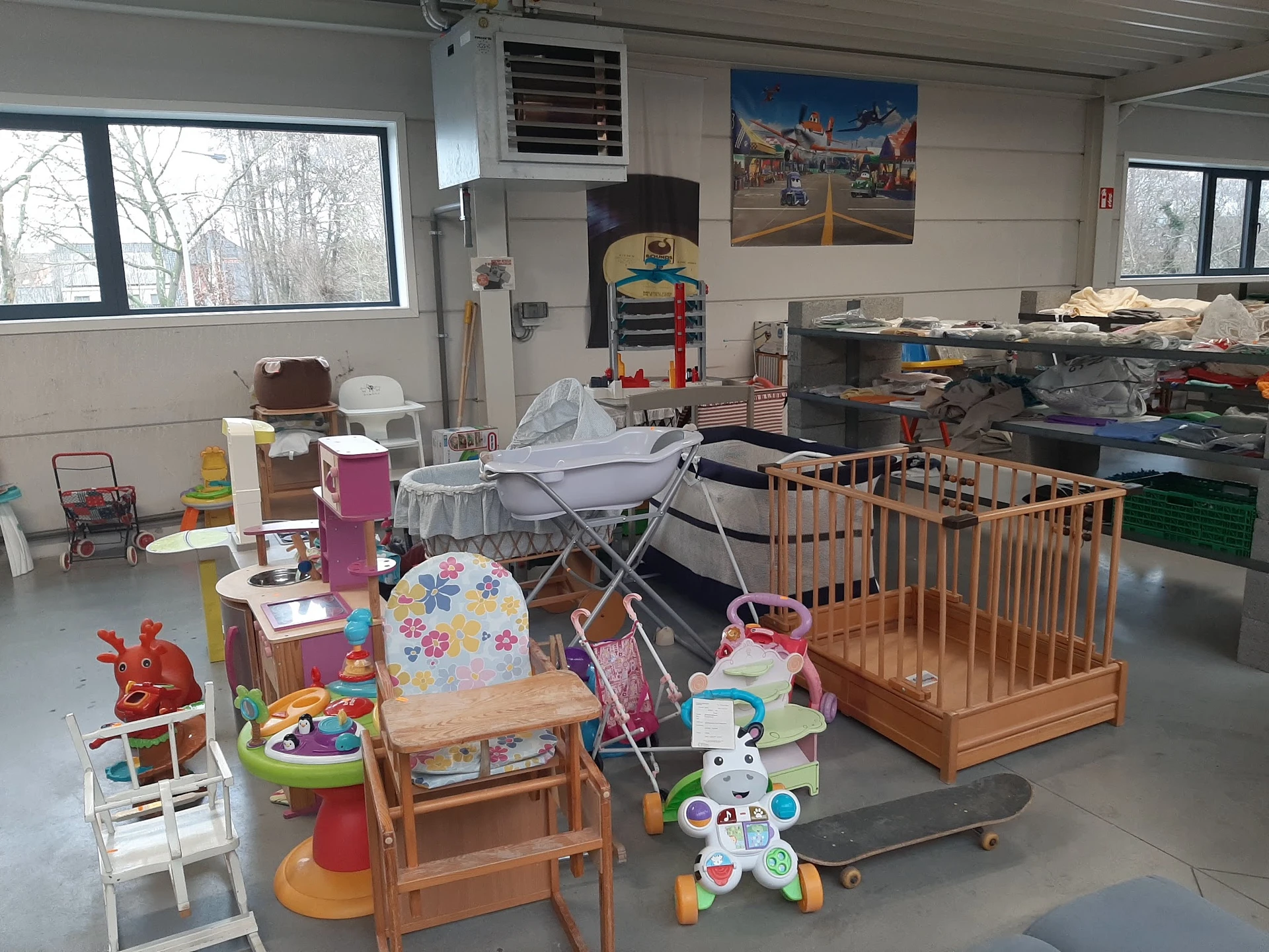 Winkelvloer met tweedehands babymeubilair en speelgoed, waaronder een wieg, kinderstoeltjes en diverse speelgoedartikelen