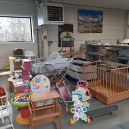 Winkelvloer met tweedehands babymeubilair en speelgoed, waaronder een wieg, kinderstoeltjes en diverse speelgoedartikelen