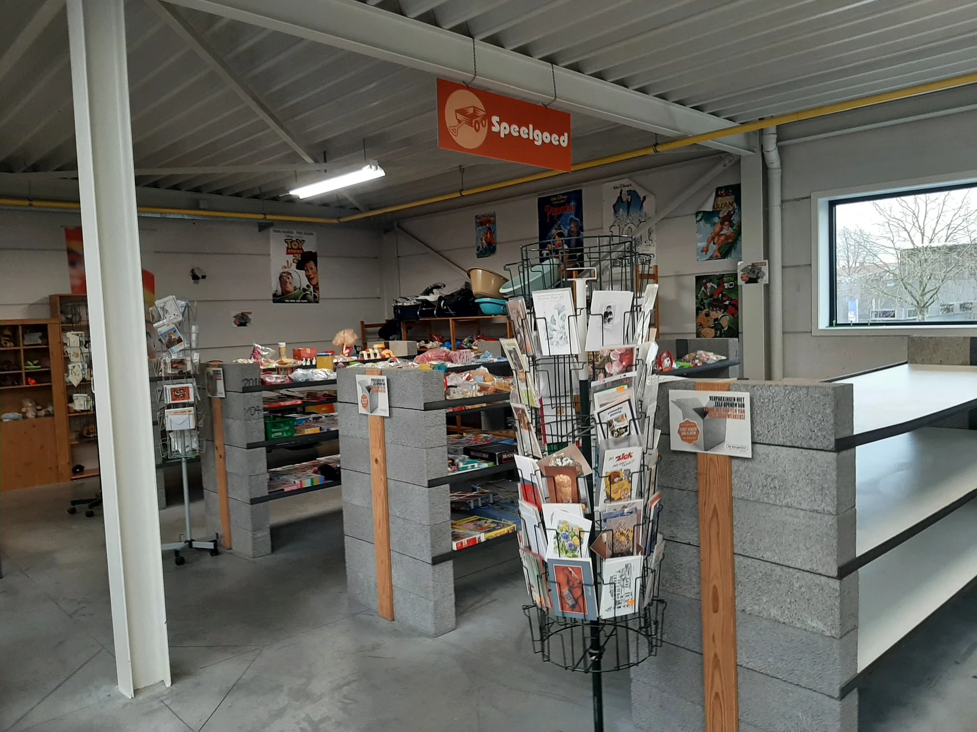 Winkelvloer met stellingen, display met kranten/tijdschriften en Speelgoed-bord aan het plafond