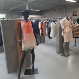 Kledingrekken met tweedehands dames- en herenkleding op etalagepoppen in een kringloopwinkel