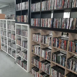 Uitgestalde dvd- en blu-ray-collecties op houten en witte stellingen in een kringloopwinkel