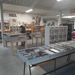 Winkelvloer met tafels vol cd's en dvd's, boekenkasten en muziekalbums in kringloopwinkel