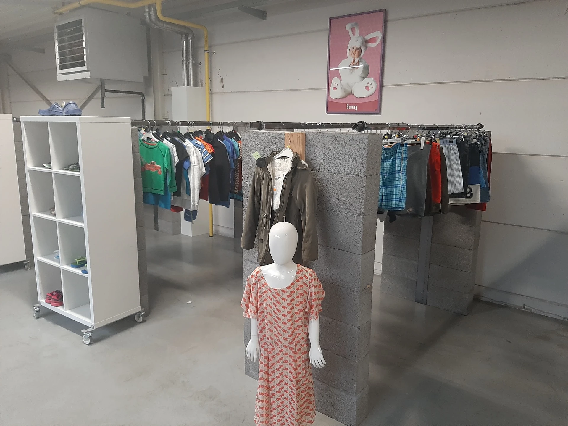 Tweedehands kleding op hangers en mannequins in de winkel