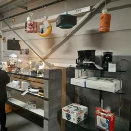 Winkelbinnenkant met toonbank, koffieapparaten en hangdecoratie in een kringloopwinkel