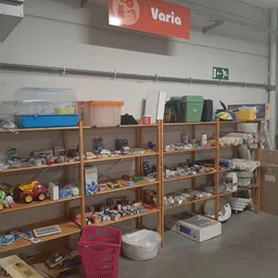 Houten stellingen met diverse tweedehands artikelen: speelgoed, huishoudelijke spullen en overige gebruiksartikelen