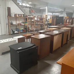 Winkelinterieur met houten meubels, kasten en tafels uitgestald op betonnen vloer onder fluorescerende verlichting