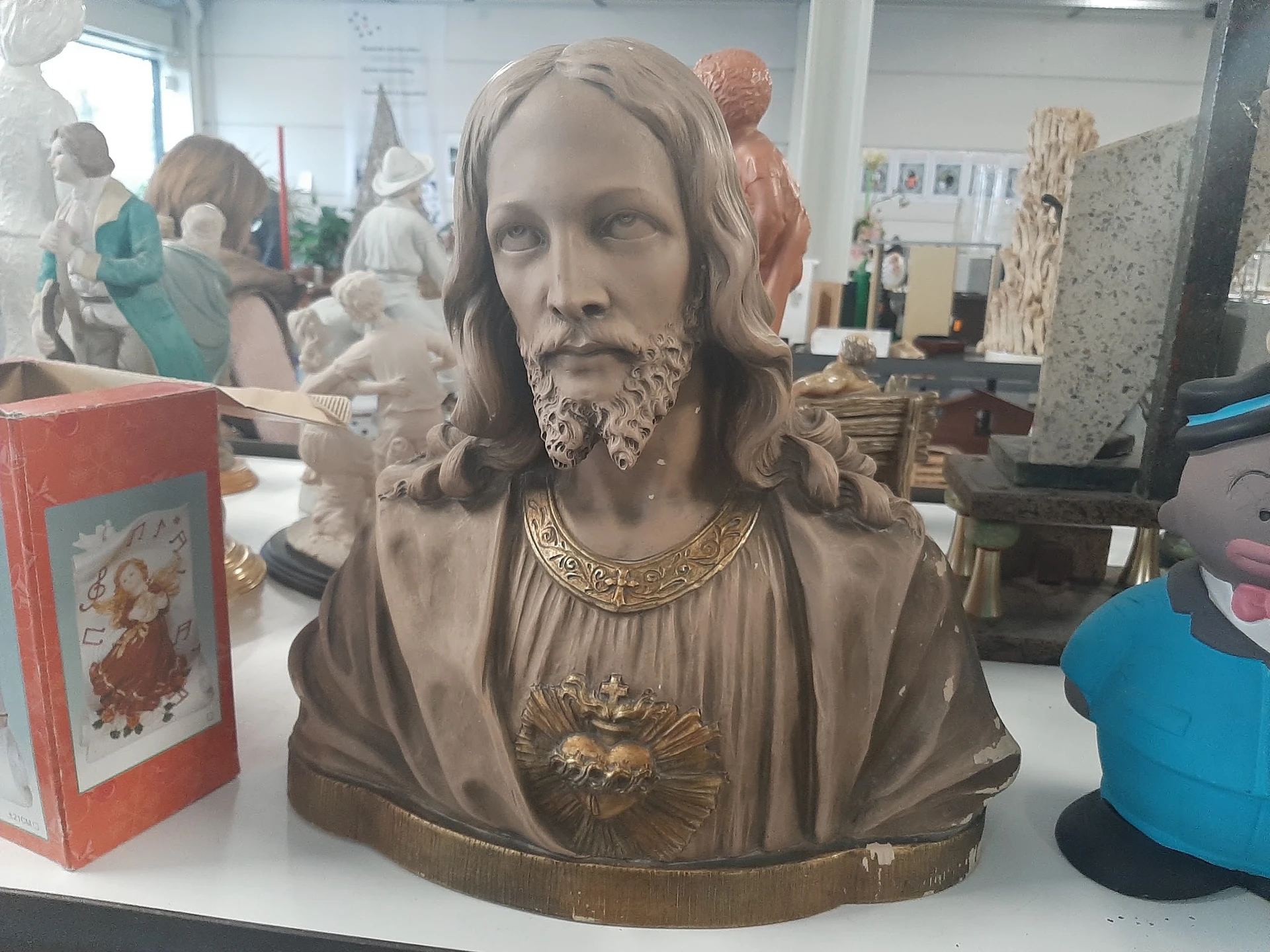 Bronzen buste van een man met lang haar en baard, dragende een gewad met hartmotief en ketting