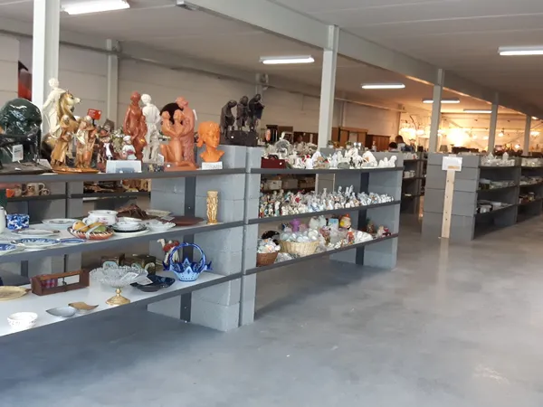Winkelvloer met grijze stellingen vol beeldjes, servies, decoratieartikelen en huishoudspullen