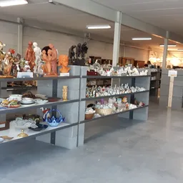 Winkelvloer met grijze stellingen vol beeldjes, servies, decoratieartikelen en huishoudspullen