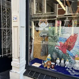 Winkelruit met uitgestalde artikelen: houten speelgoed, porseleinen figuurtjes en decoratieve items op blauwe ondergrond