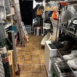 Winkelgang met stellingen, dozen en diverse spullen langs de muren