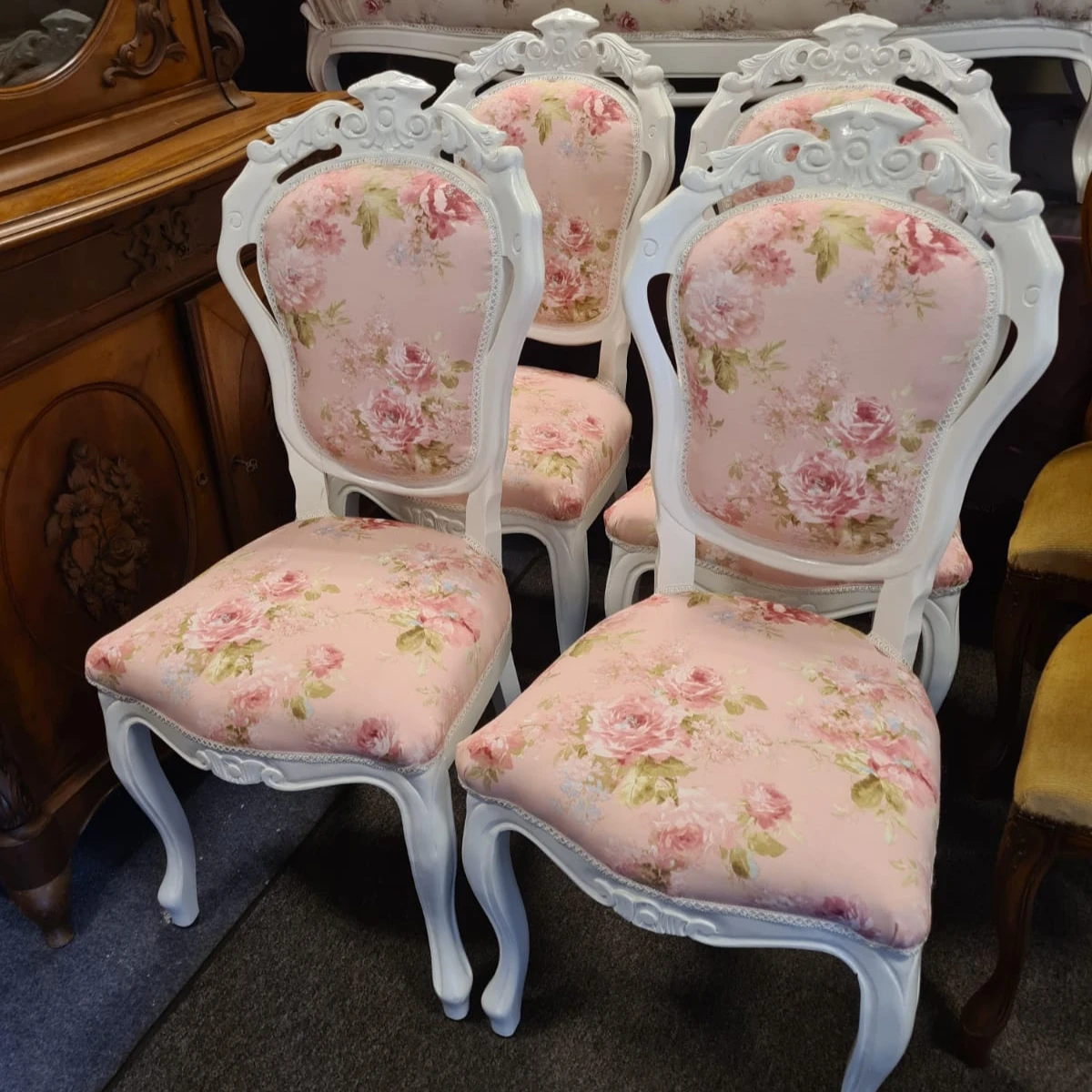 Twee witte barokstijl stoelen met roze bloemdessin bekleding