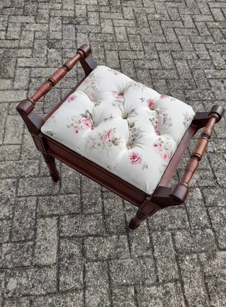 Houten kruk met roze en witte bloemenprint kussen op tegelvloer