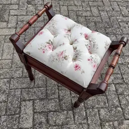 Houten kruk met roze en witte bloemenprint kussen op tegelvloer