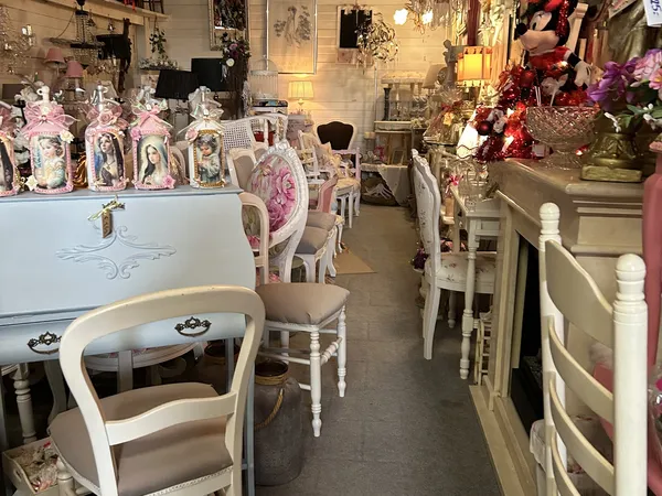Winkelinterieur met witte meubels, stoelen, decoratieve items en bloemen op stellingen