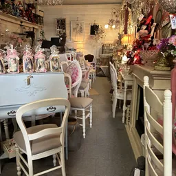 Winkelinterieur met witte meubels, stoelen, decoratieve items en bloemen op stellingen