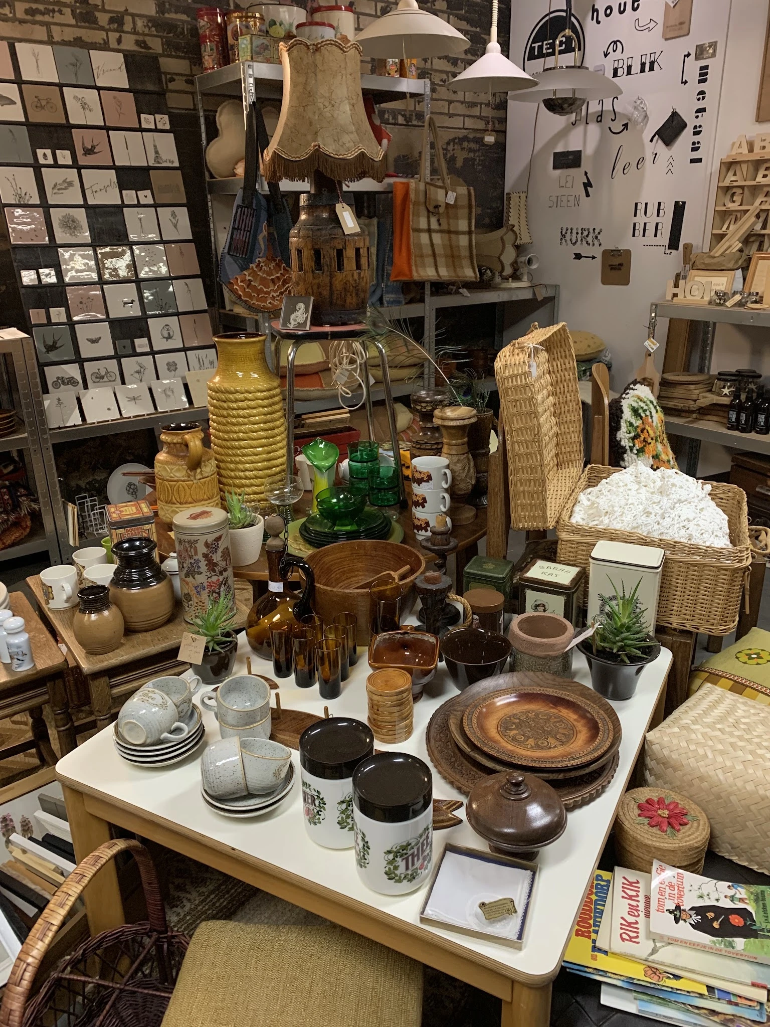 Uitgestalde huishoudartikelen en decoratie: servies, kandelaars, wicker manden, glazen flessen en houten schalen