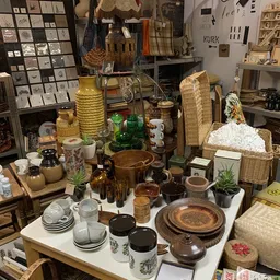 Uitgestalde huishoudartikelen en decoratie: servies, kandelaars, wicker manden, glazen flessen en houten schalen