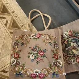 Close-up van een vintage jute tas met bloemenborduurwerk in roze en rode tinten