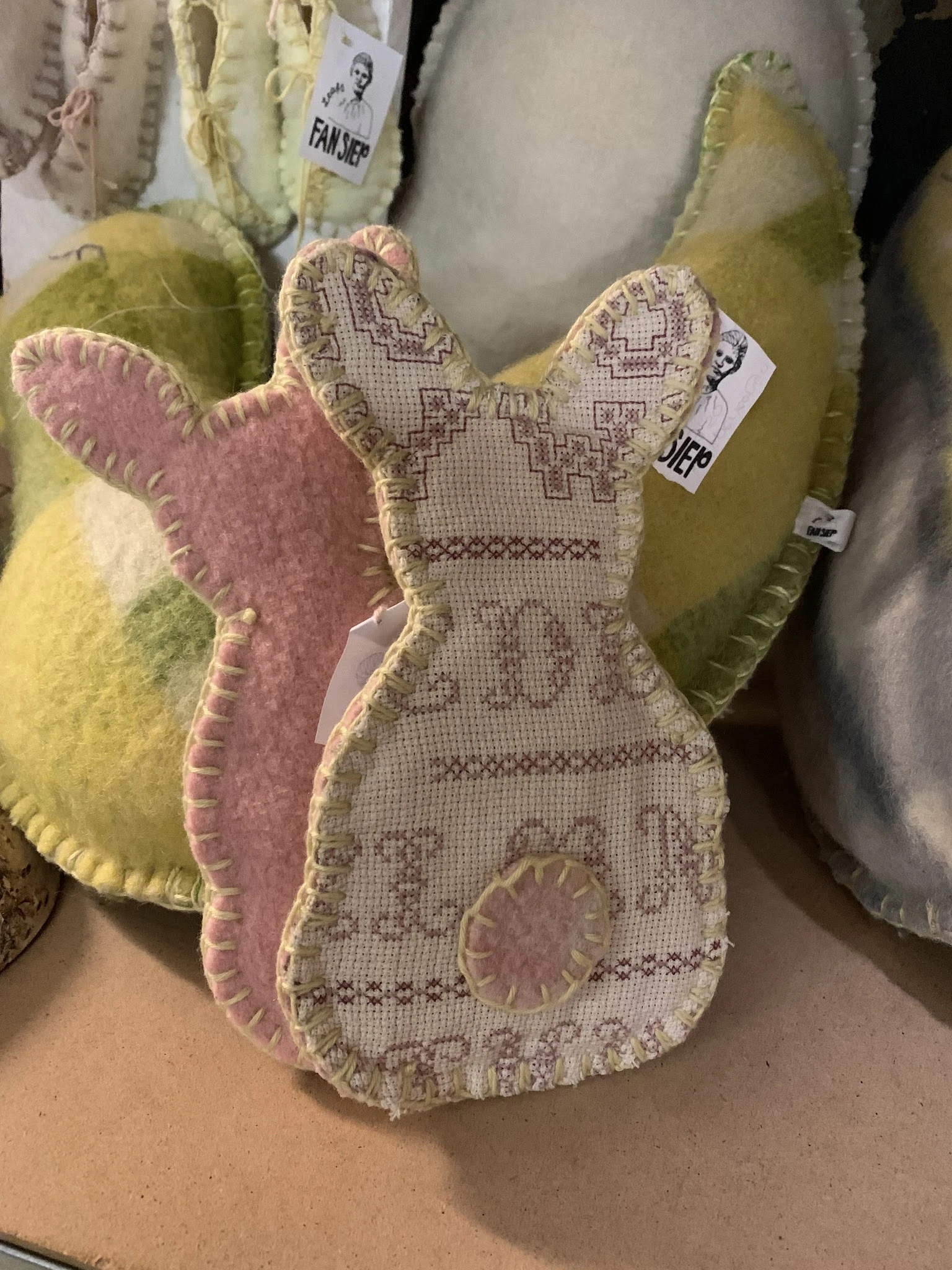 Close-up van een roze en beige konijn-vormige kussen of knuffel met geborduurd patroon