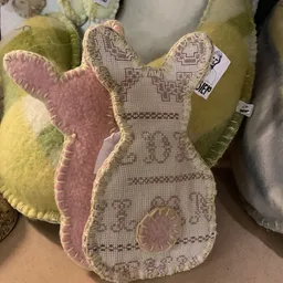 Close-up van een roze en beige konijn-vormige kussen of knuffel met geborduurd patroon