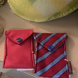 Twee rode portemonnees met blauwe knoopsluiting, één effen en één met blauwe strepenpatroon