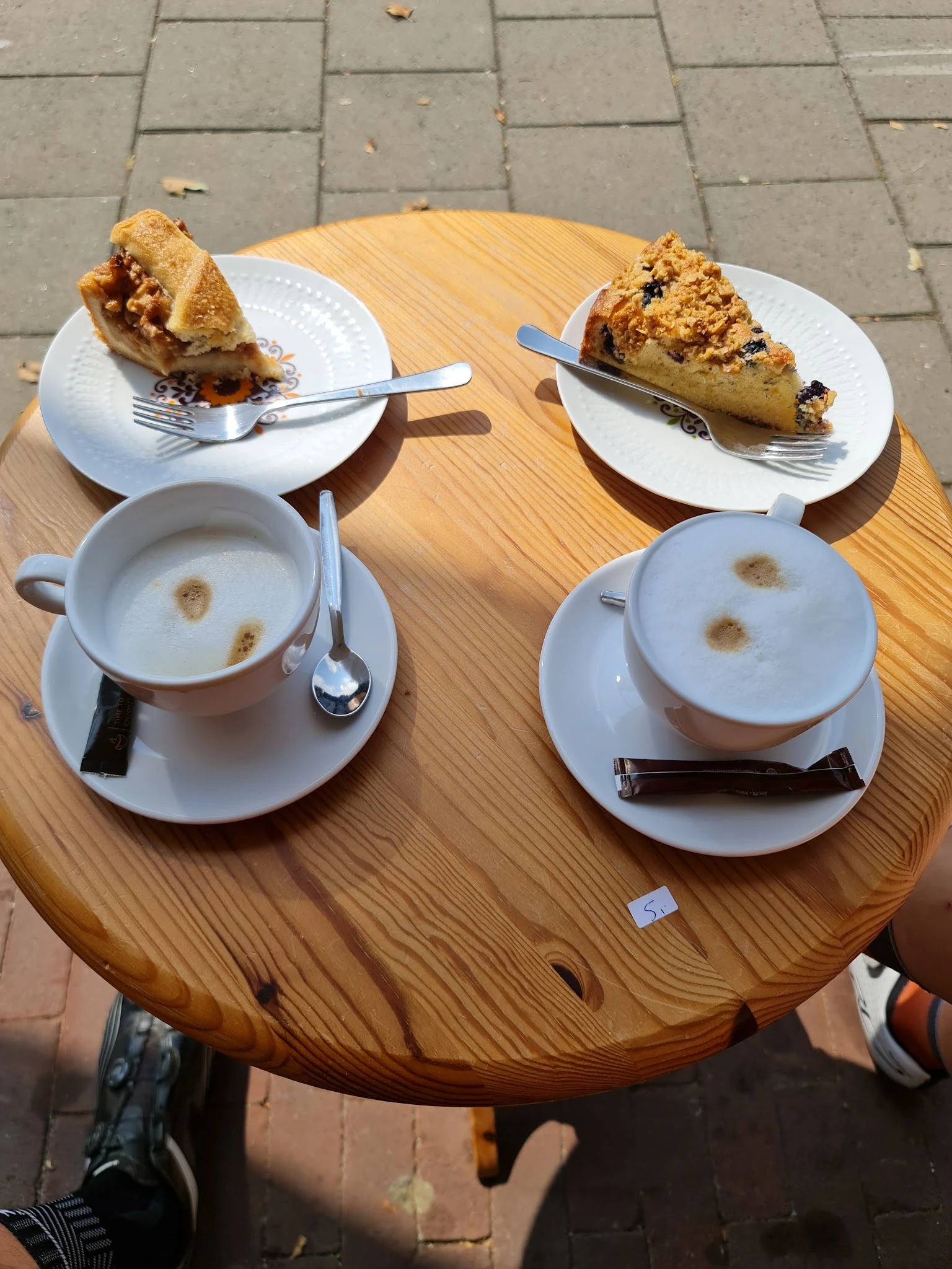 Twee kopjes koffie en twee gebakjes op houten tafel in een lunchroom
