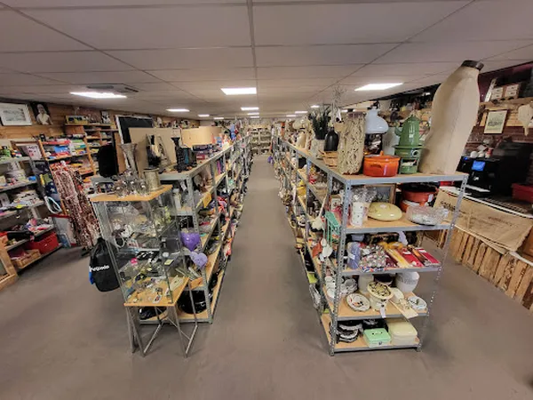 Winkelvloer van kringloopwinkel met gele stellingen vol tweedehands spullen aan beide zijden