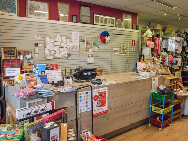 Toonbank en winkelruimte met slatwalls, uitgestalde spullen, decoratie en handelswaar in een kringloopwinkel