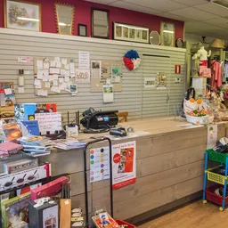 Binnenzicht van kringloopwinkel met toonbank, stellingen aan muren, diverse artikelen en decoratie
