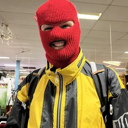 Persoon met rode bivakmuts en geel-zwart jack in winkelinterieur