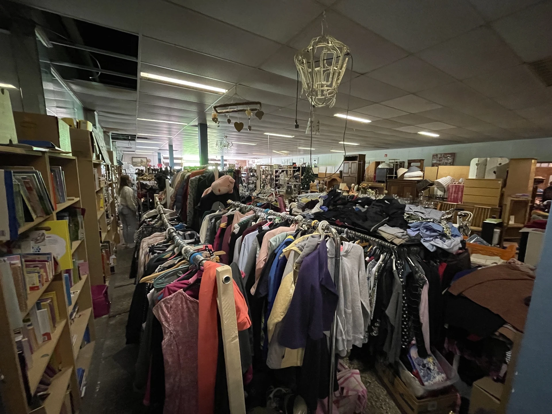 Rekken met tweedehands kleding in verschillende kleuren in een kringloopwinkel