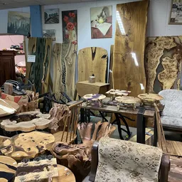 Uitgestalde houten meubels en decoratieve objecten in de kringloopwinkel, waaronder houten panelen, sculpturen en handwerk.