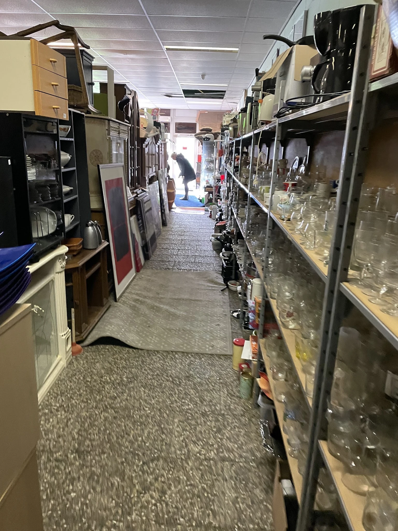 Winkelgang met stellingen vol glazen en servies aan beide zijden