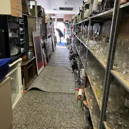 Winkelgang met stellingen vol glazen en servies aan beide zijden