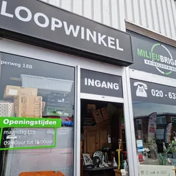 Gevel van Milieu Brigade Kringloopwinkel met uithangbord, winkelraam en ingang aan Slijperweg