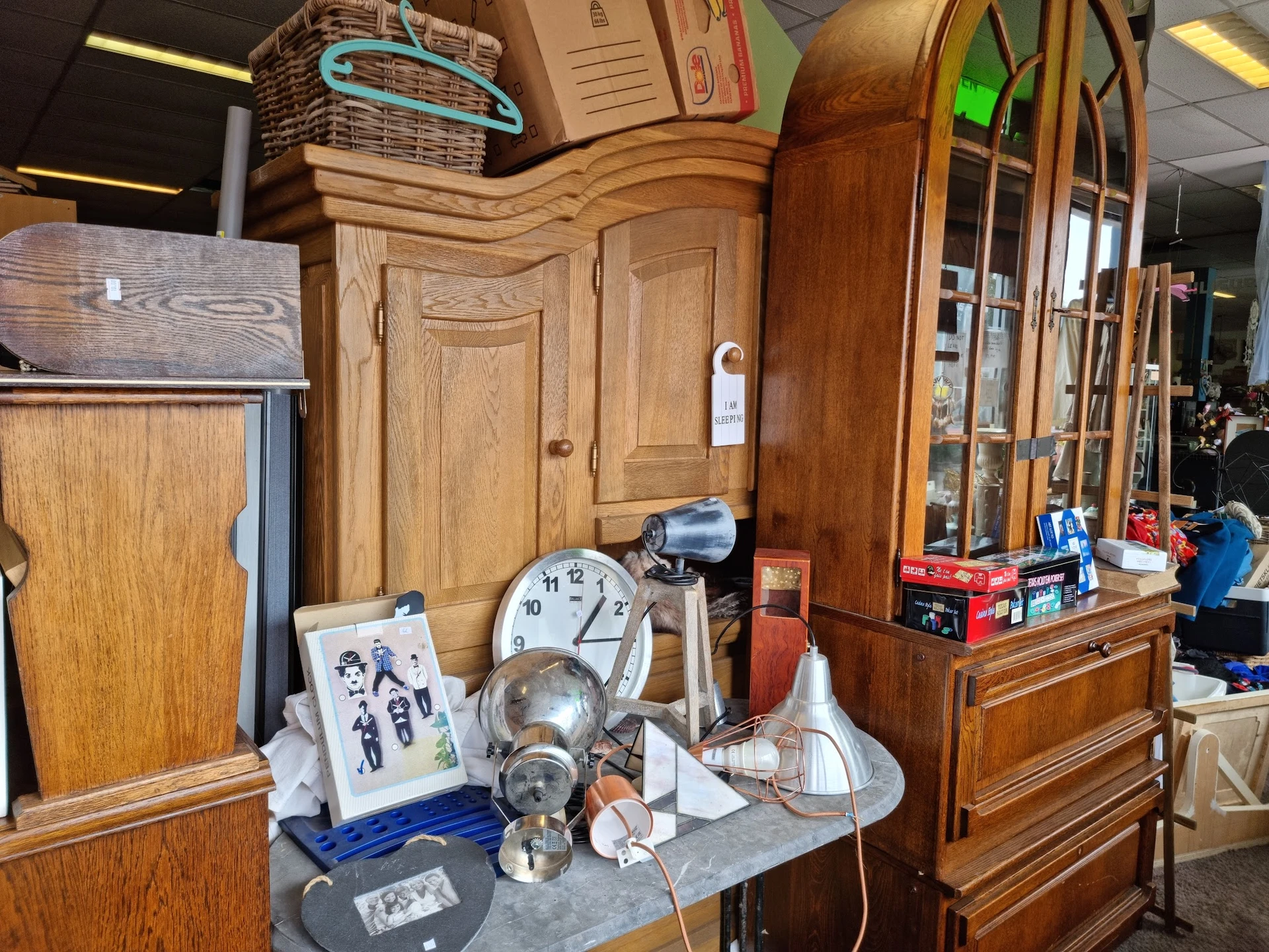 Houten meubels en huishoudartikelen op display, waaronder kasten, klok en diverse spullen